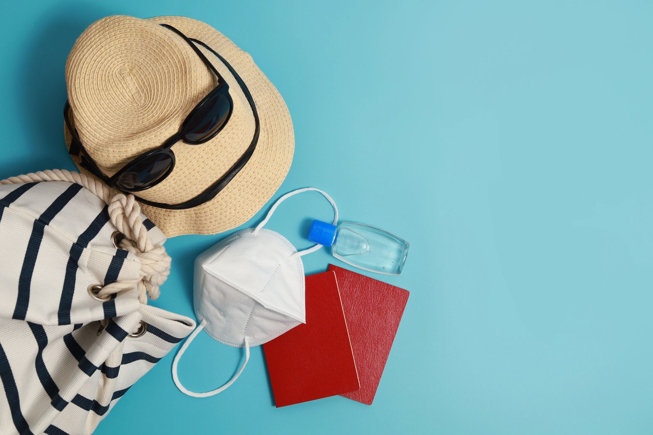 Flat lay of travel items including passport and essentials on a blue background